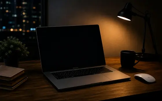 Laptop przy zapalonej lampce na ciemnym biurku
