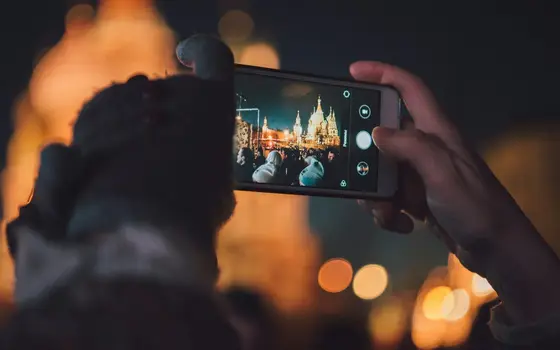 Robienie zdjęcia telefonem nocą, w tle światła miasta