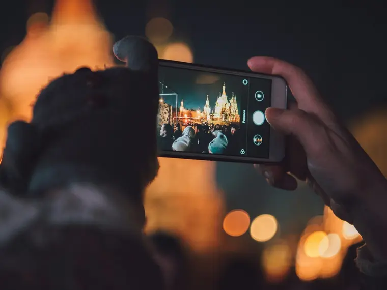 Robienie zdjęcia telefonem nocą, w tle światła miasta