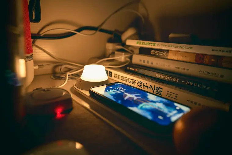 Telefon na stoliku nocnym przy zapalonej lampce