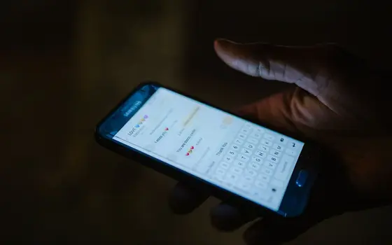 Dłoń z telefonem i otwartymi wiadomościami w ciemności