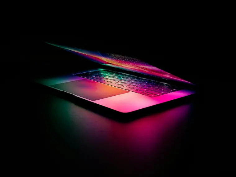 Uchylony laptop z kolorowym podświetleniem w ciemności