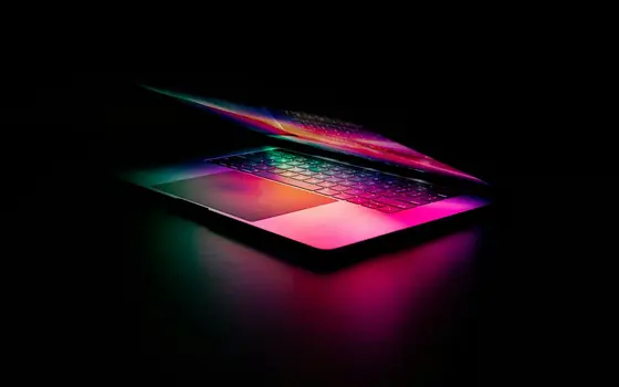 Uchylony laptop z kolorowym podświetleniem w ciemności