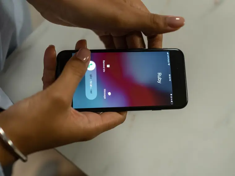 Dłonie trzymają telefon z przychodzącym połączeniem