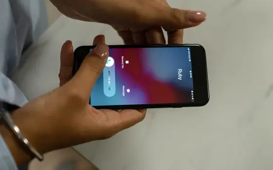 Dłonie trzymają telefon z przychodzącym połączeniem