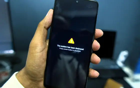 Dłoń trzyma telefon z ostrzeżeniem na ekranie w ciemności